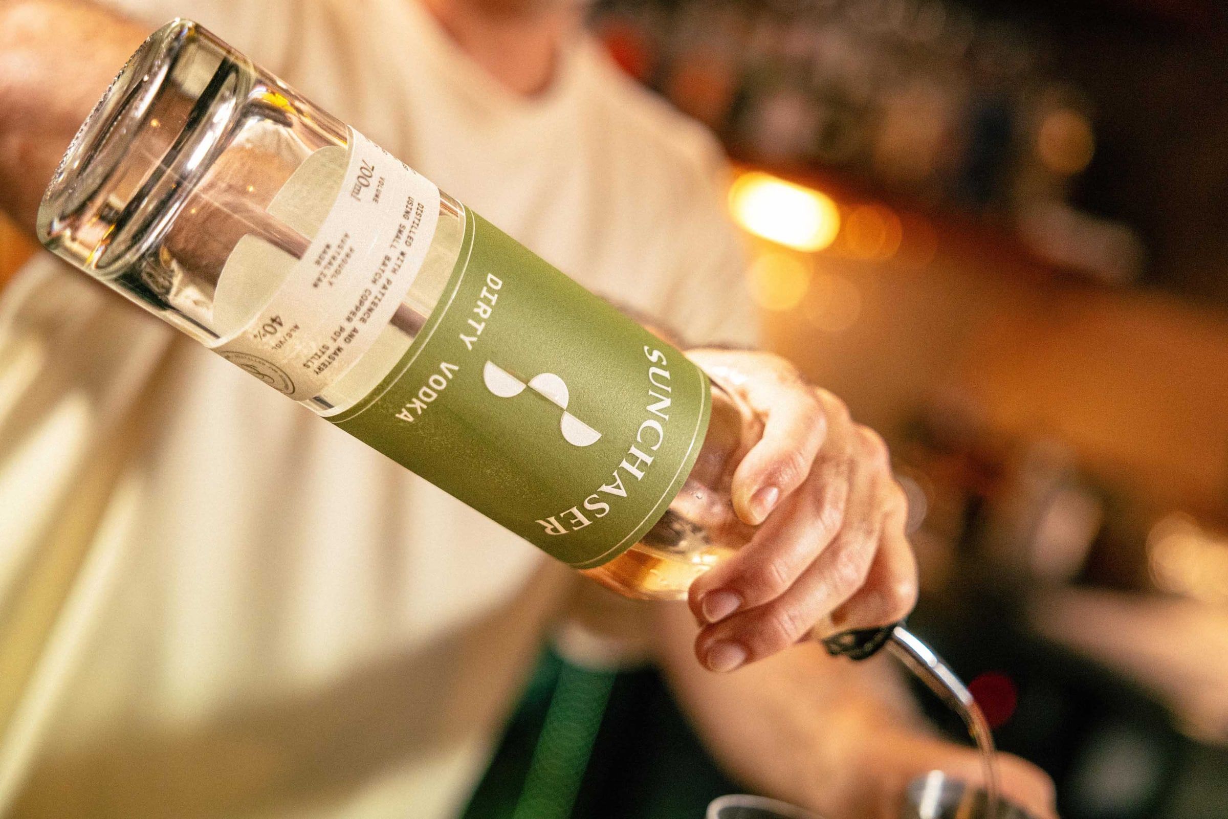 A bartender pours Sunchaser Dirty Vodka through a pourer into a jigger.