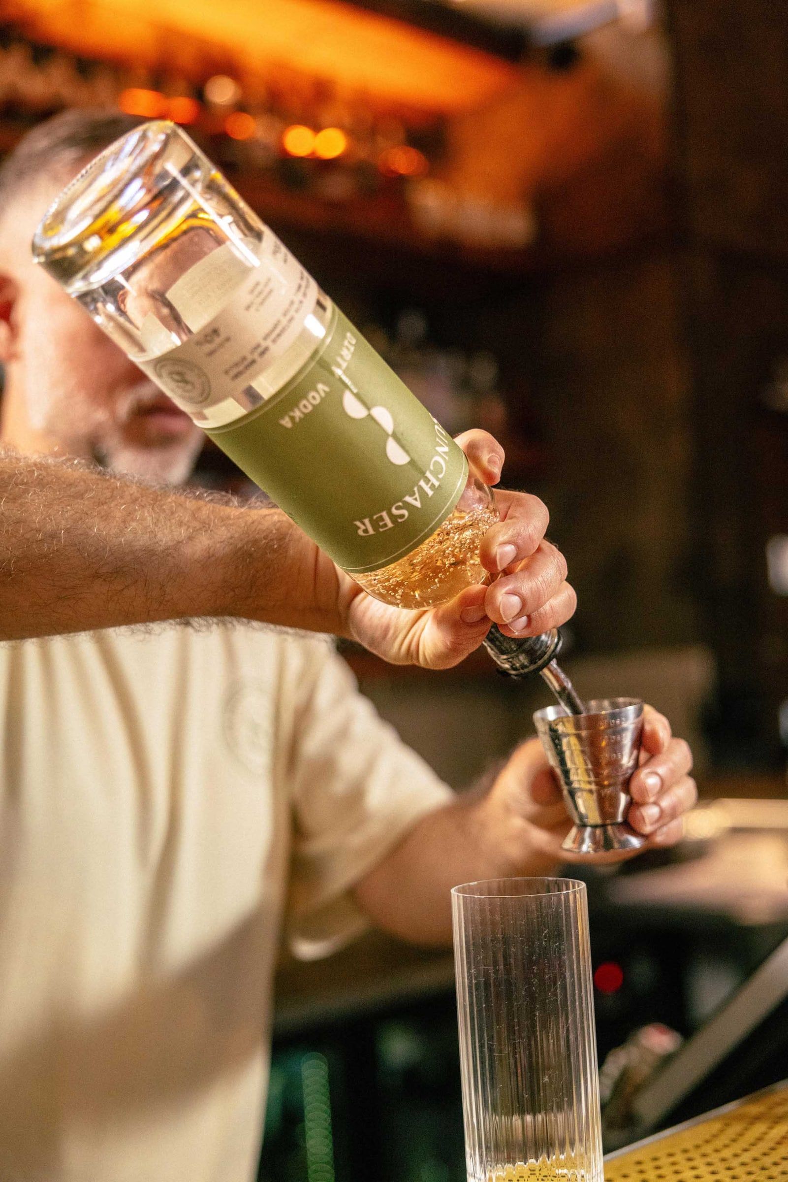 A bartender pours Sunchaser Dirty Vodka from the bottle into a jigger.