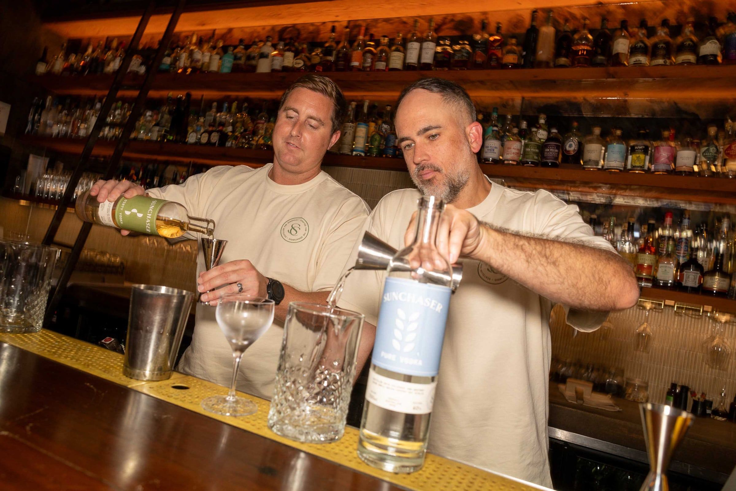 The founders pouring Sunchaser Pure and Dirty Vodka behind the bar.